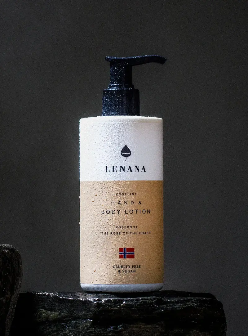 Hand und Body Lotion Flasche ist ruhig orange Farbe mit norwegischen Flagge und cruelty free &amp; vegan Label. Die Flasche ist in Wassertropfen und steht auf einem dunklen Stein