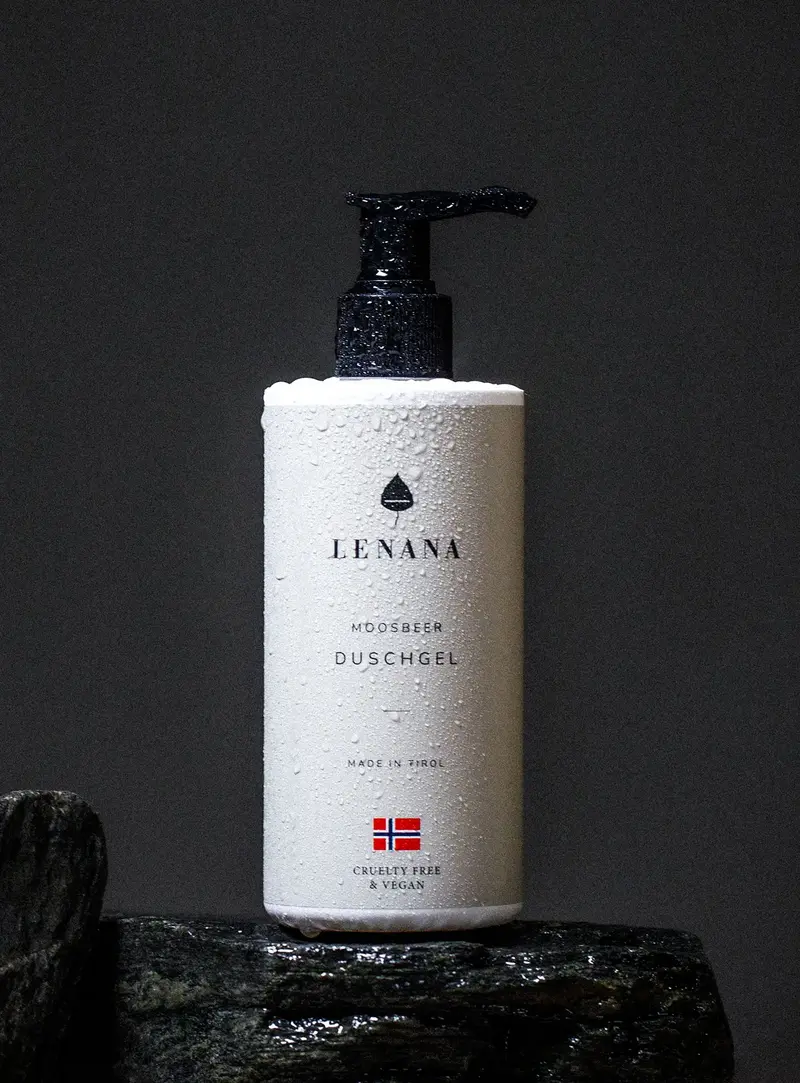 Duschgel-Flasche ist Pastell-Creme Farbe mit norwegischen Flagge und cruelty free &amp; vegan Label. Die Flasche ist in Wassertropfen und steht auf einem dunklen Stein